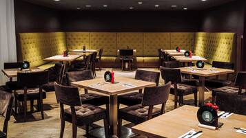 A restaurant with booths and tables, each set with cutlery and a red decorative item.