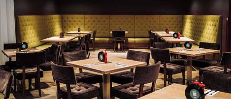 A restaurant with booths and tables, each set with cutlery and a red decorative item.