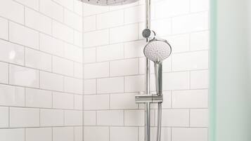 Ducha con cabezal de ducha de mano y ducha lluvia, montada en una pared con azulejos blancos.