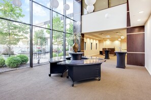 A modern interior with glass walls, a reception desk, and a seating area with tables and chairs. - DoubleTree by Hilton Hotel Binghamton (Binghamton)