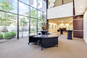 A modern interior with glass walls, a reception desk, and a seating area with tables and chairs.