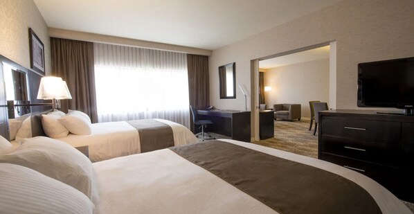 A hotel room with two beds, a desk, a chair, a TV, and a large window with curtains. - DoubleTree by Hilton Hotel Binghamton (Binghamton)