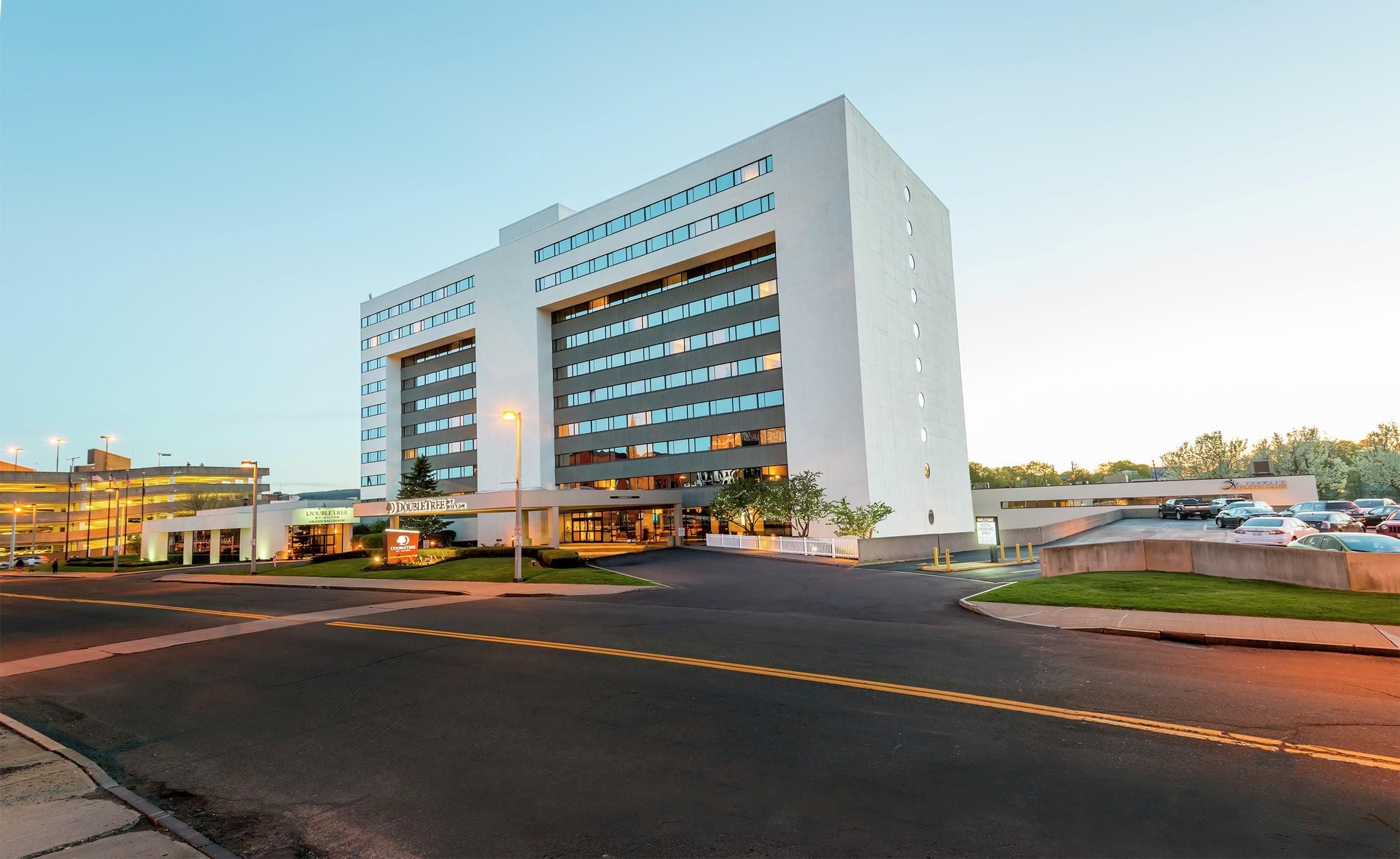 A modern hotel with a two-story structure, a covered entrance, and a parking lot.