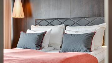A neatly made bed with a red and white bedspread, grey and white pillows, and a wooden headboard.