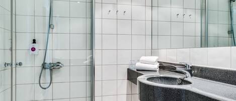 Un baño moderno con cabina de ducha de vidrio, lavamanos de granito y espejo.