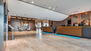 A modern hotel lobby with a reception desk, seating area, and a large mirror. - Quality Airport Hotel Stavanger (Sola)