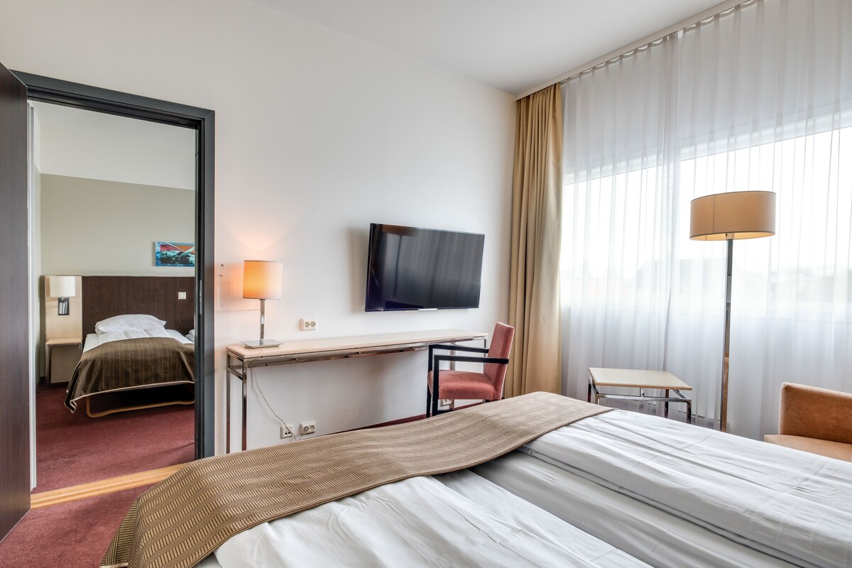 Een hotelkamer met een bed, een bureau, een stoel, een televisie en een lamp.
