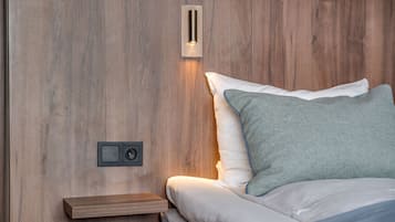 Un dormitorio con pared de madera, una mesita de noche, una lámpara de pared y una cama con ropa de cama blanca y turquesa.