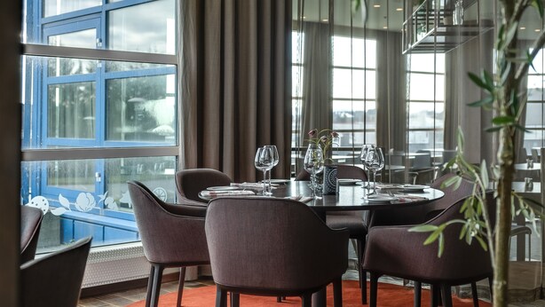 A dining area with a table set for four, large windows, and a potted plant. - Quality Airport Hotel Stavanger (Sola)