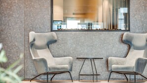 A modern interior with two upholstered chairs and a small table, a textured wall, and a window with a view. - Quality Airport Hotel Stavanger (Sola)