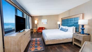 Una habitación de hotel con una cama grande, televisión, escritorio y vista al mar.