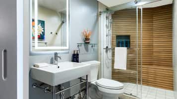 Un baño moderno con lavamanos blanco, inodoro y cabina de ducha de cristal.