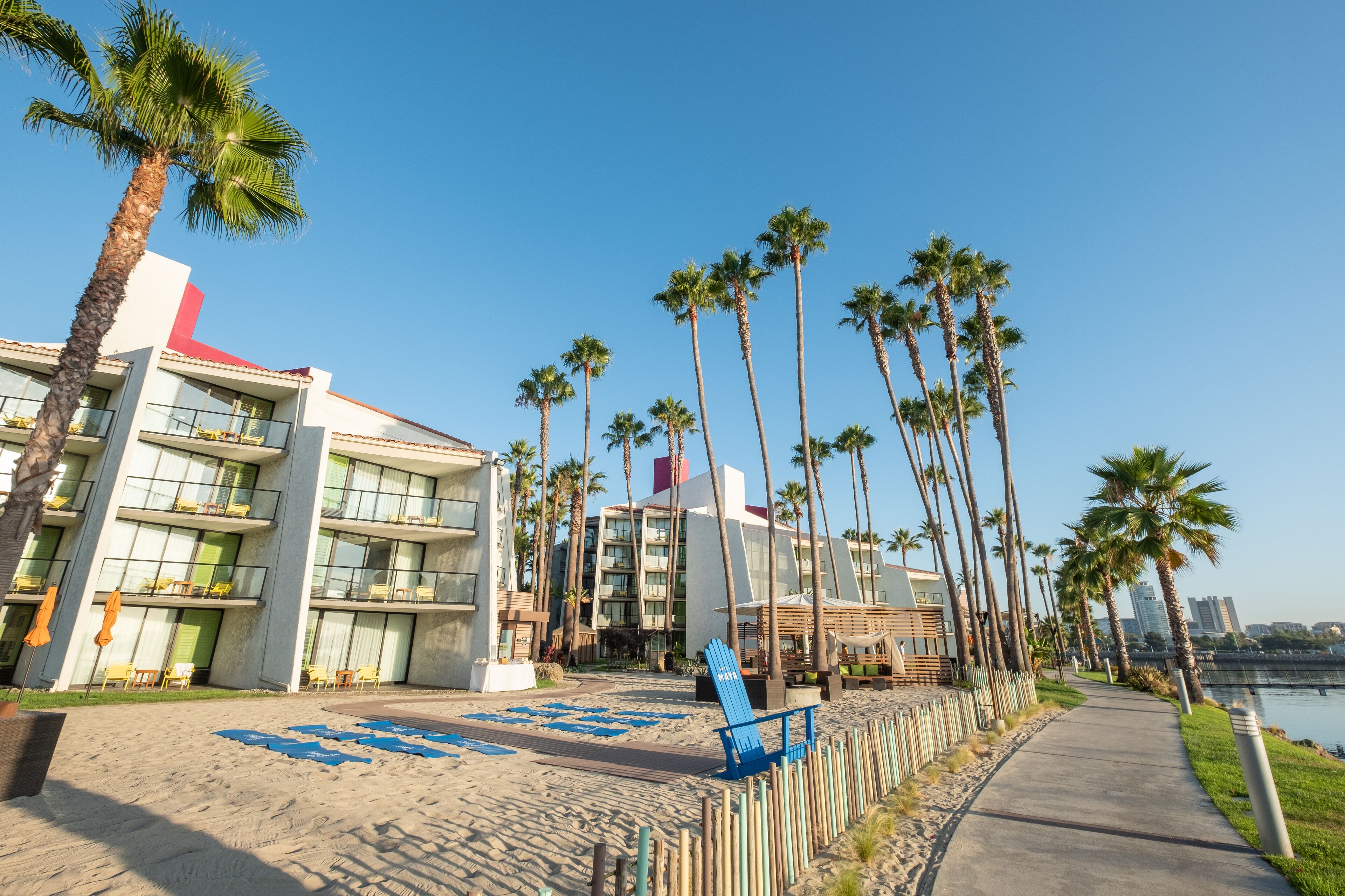 A beachfront hotel with multiple floors, palm trees, and a clear view of the water.