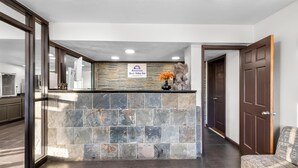 A reception area with a stone wall, a sign for 'Americas Best Value Inn', and a statue. - Americas Best Value Inn Kansas City E Independence (Independence)
