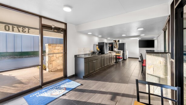 A modern kitchen with a large island, a dining area with a table and chairs, and a view through the glass door to the outside. - Americas Best Value Inn Kansas City E Independence (Independence)