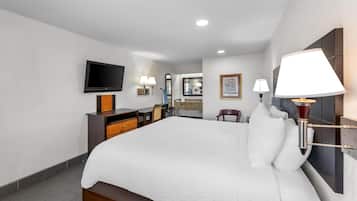 A hotel room with a large bed, a flat-screen TV, a dresser, and two wall-mounted lamps.