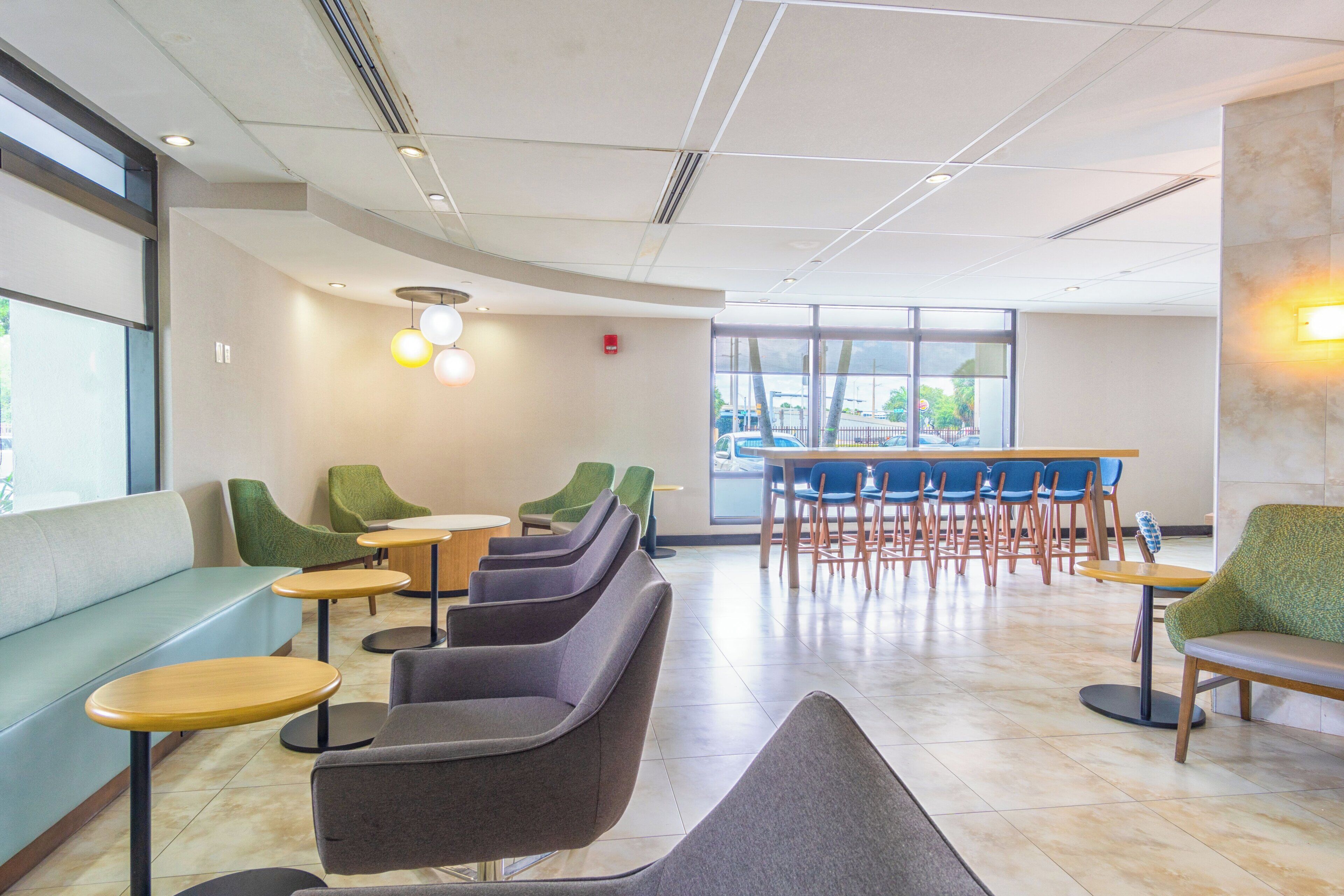 A modern interior with seating arrangements, a bar area, and large windows providing natural light.