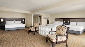 A hotel room with two beds, a desk, and two chairs.