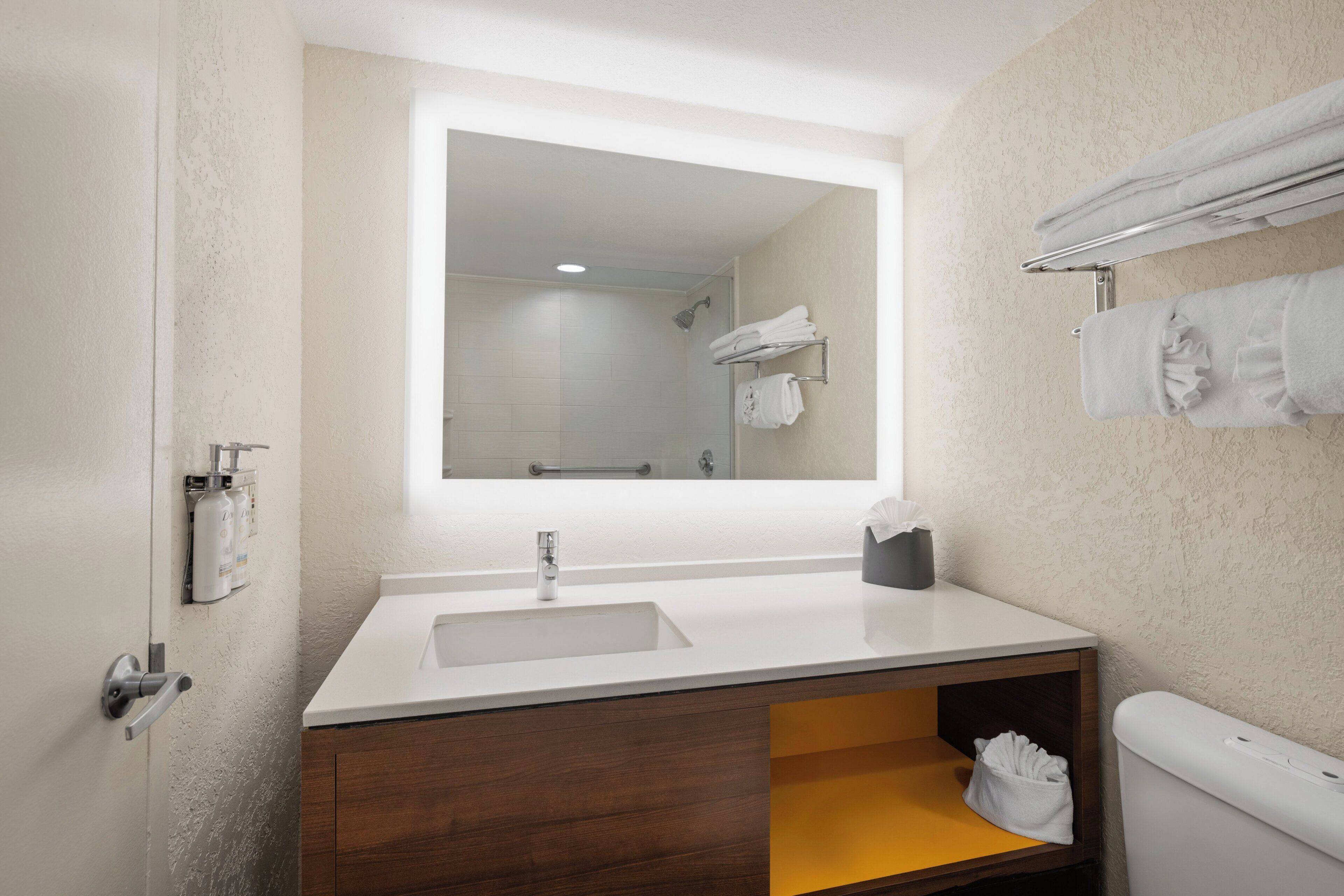 A modern bathroom with a large mirror, a sink, a toilet, and a towel rack.