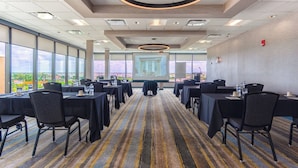 A conference room with tables, chairs, and a large screen for presentations. - Holiday Inn Miami - International Airport by IHG (Miami Springs)