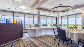 A conference room with a long table, chairs, and a bar area with bottles.