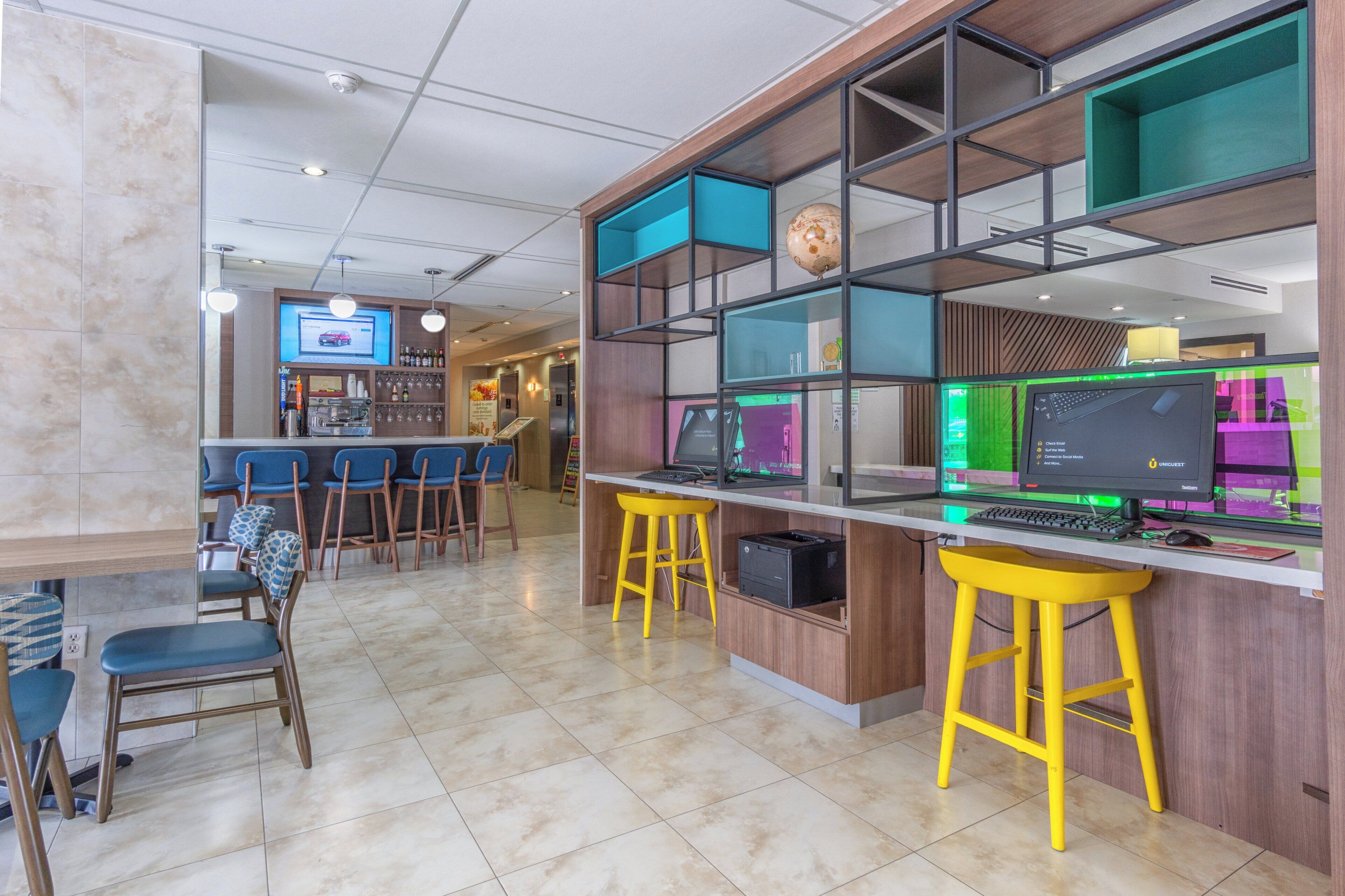 A modern workspace with multiple computers, a bar area, and seating.
