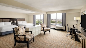 A hotel room with a bed, two chairs, a desk, a lamp, and large windows. - Holiday Inn Miami - International Airport by IHG (Miami Springs)