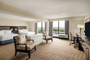 A hotel room with a bed, two chairs, a desk, a lamp, and large windows. - Holiday Inn Miami - International Airport by IHG (Miami Springs)