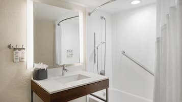 A bathroom with a white sink, mirror, shower, and bathtub.