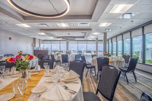 Comedor de hotel con mesas dispuestas para el servicio, ventanas amplias que ofrecen vistas y un diseño moderno de techo.