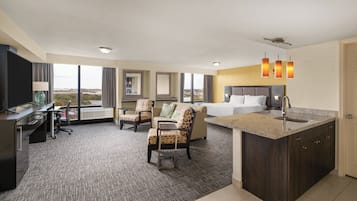Habitación de hotel con escritorio, silla de oficina, sofá y una pequeña kitchenette.