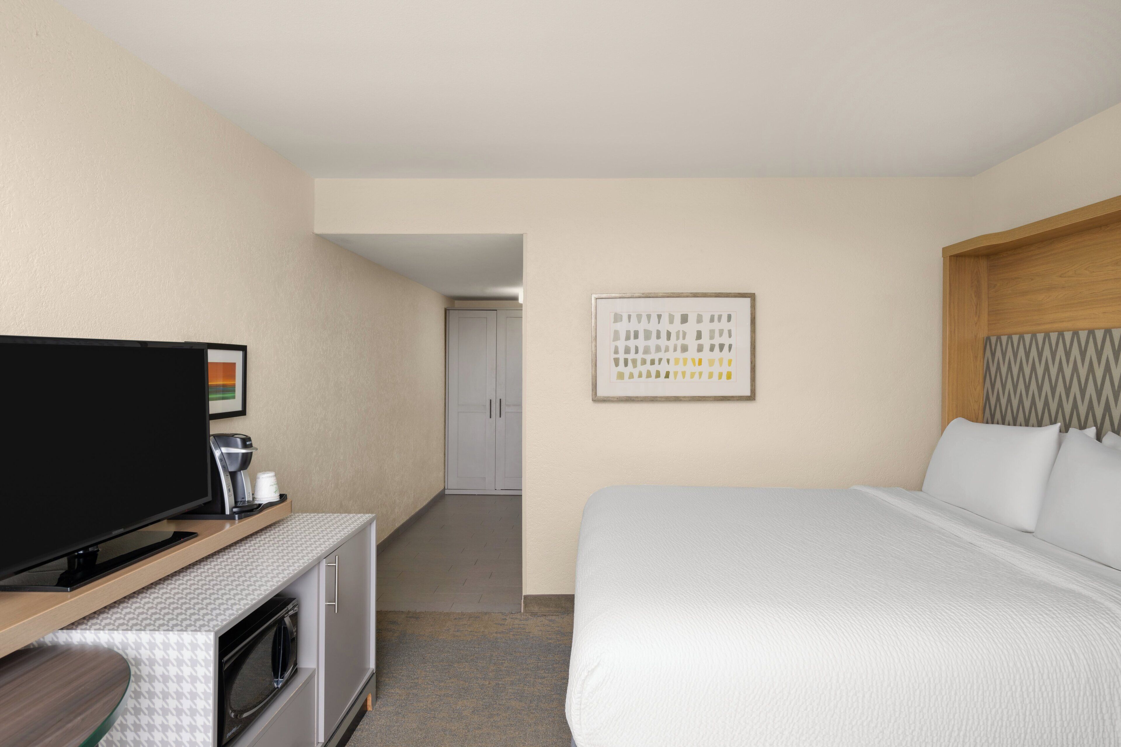 Una habitación de hotel con cama, televisión, cafetera y microondas.