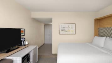 Een hotelkamer met een bed, een televisie, een koffiezetapparaat en een magnetron.