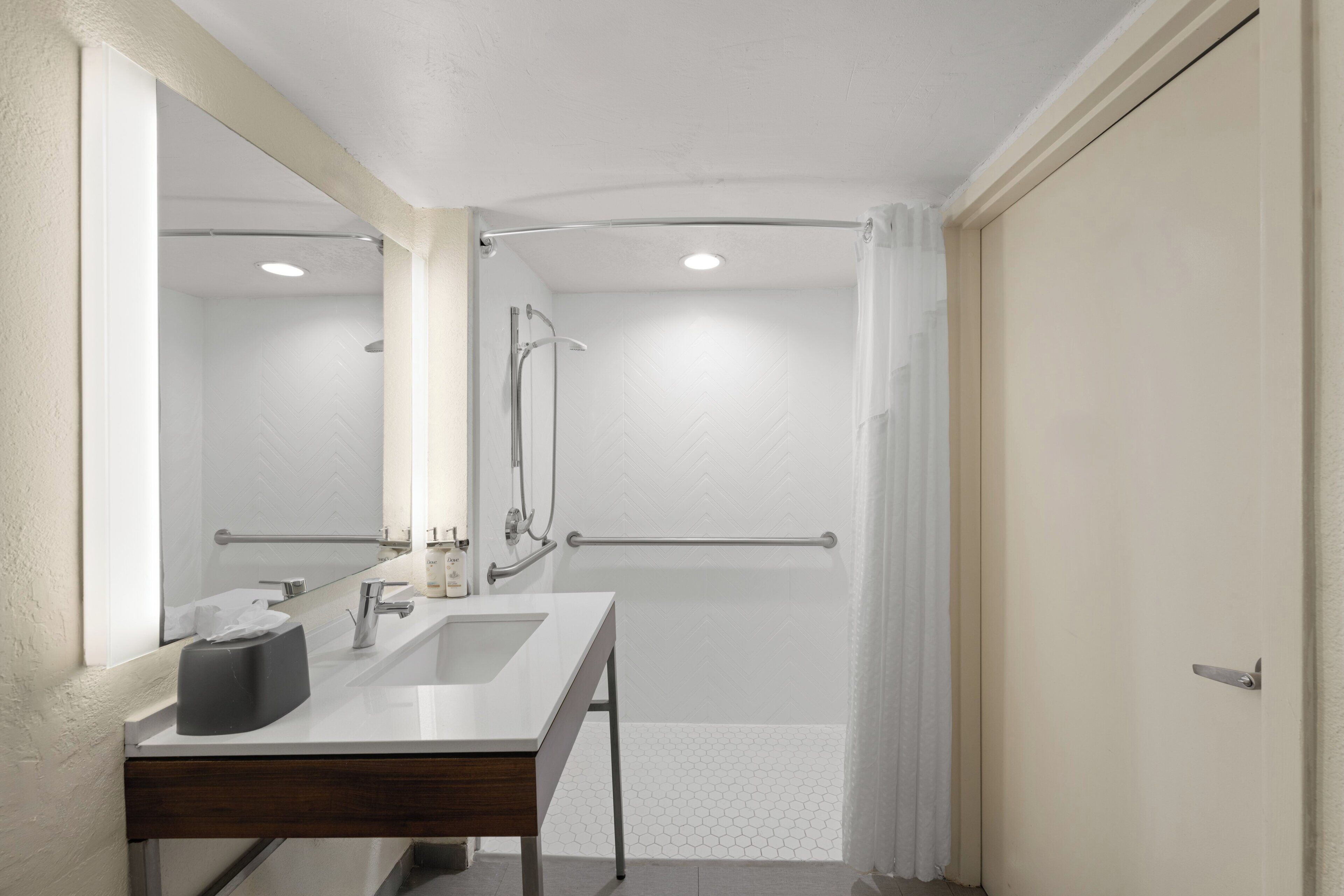A bathroom with a white sink, mirror, and shower area.