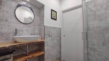 Un baño con lavamanos independiente, un espejo, baldosas estampadas y una puerta.