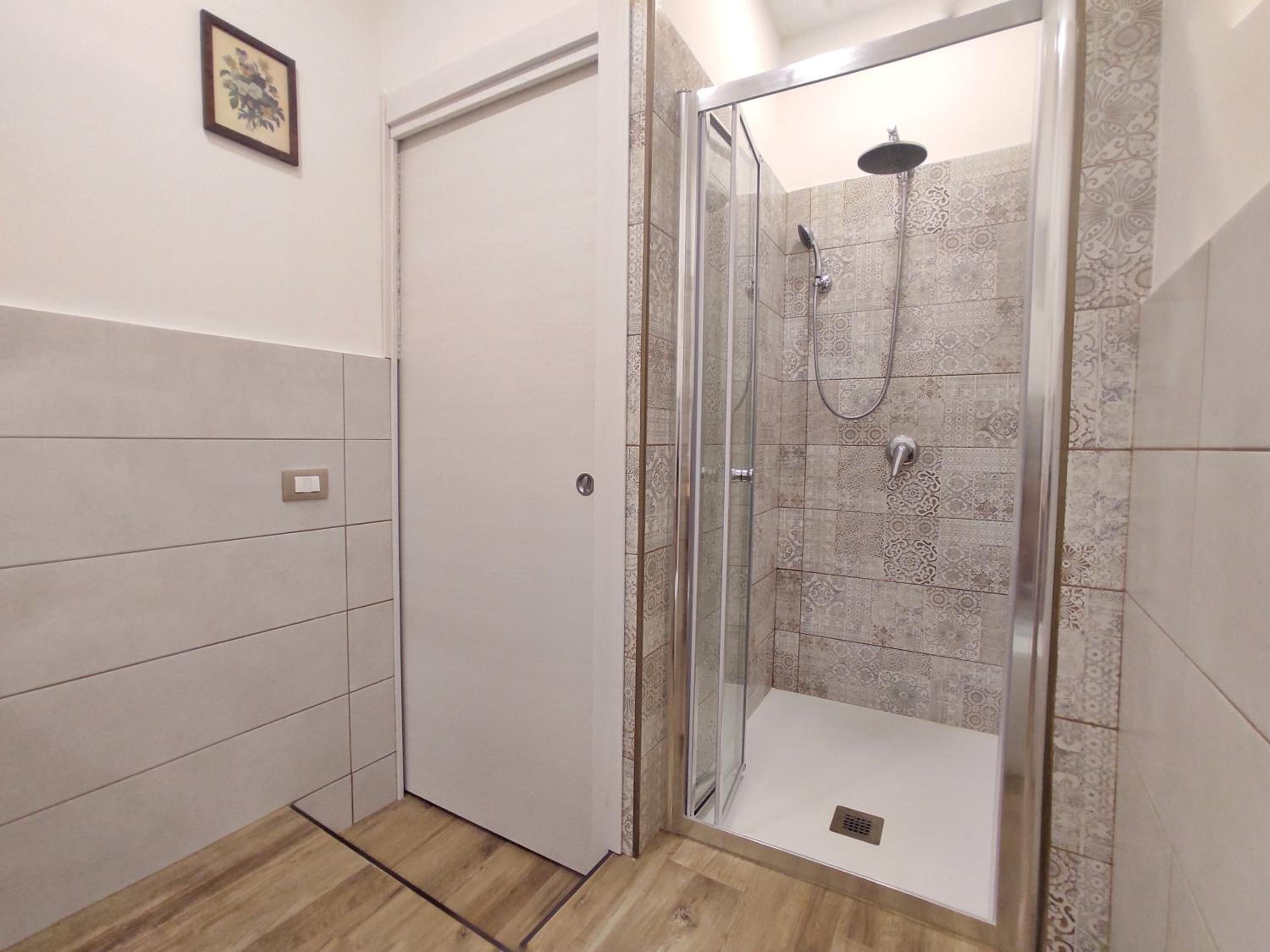 Une salle de bain moderne avec une douche à parois de verre, des carreaux décoratifs et un plancher en bois.