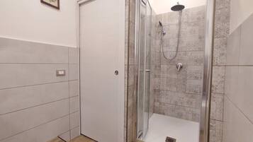 Un baño moderno con ducha envuelta en vidrio, azulejos estampados y suelo de madera.