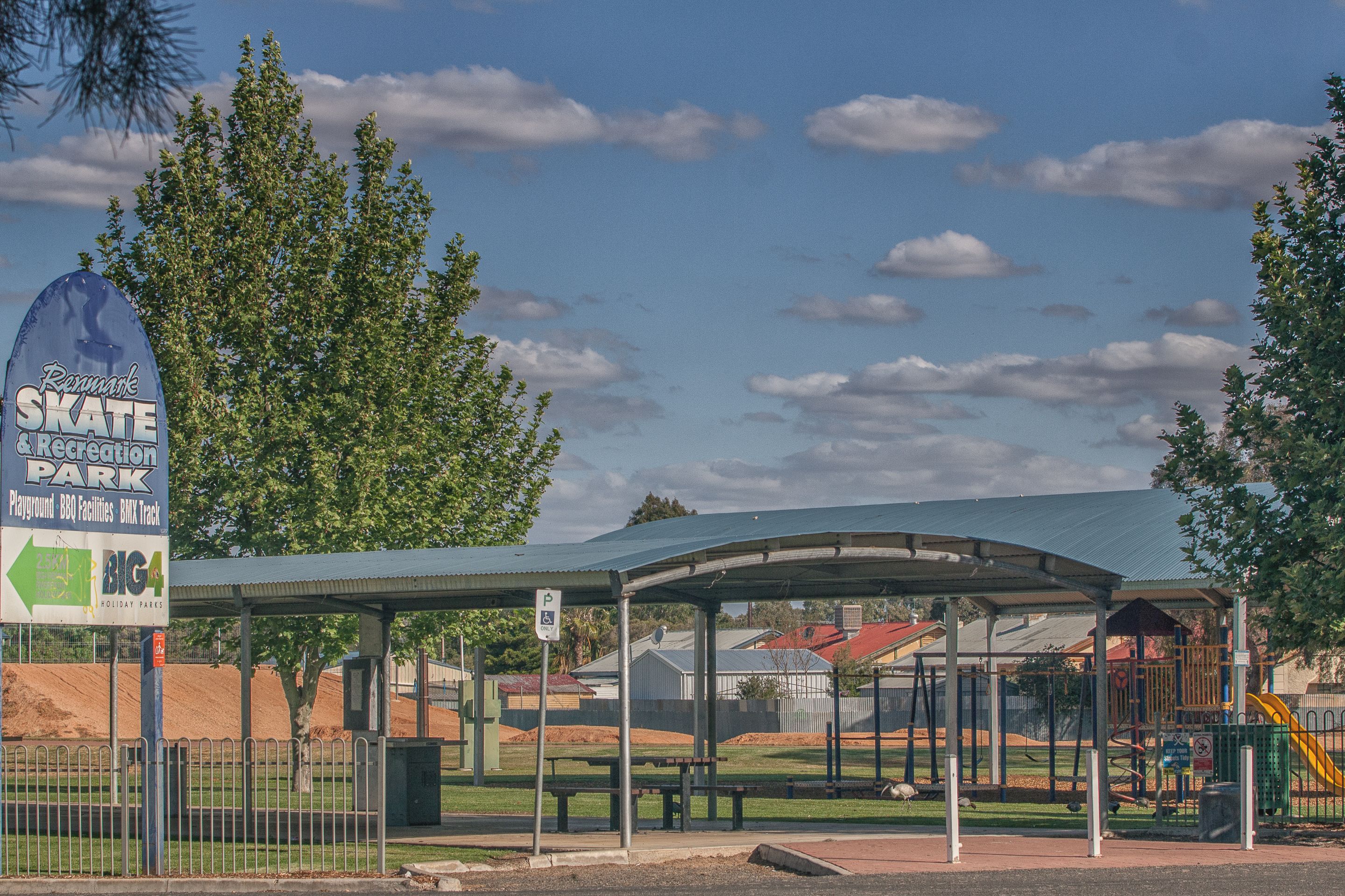 A covered picnic area with a playground in the background.