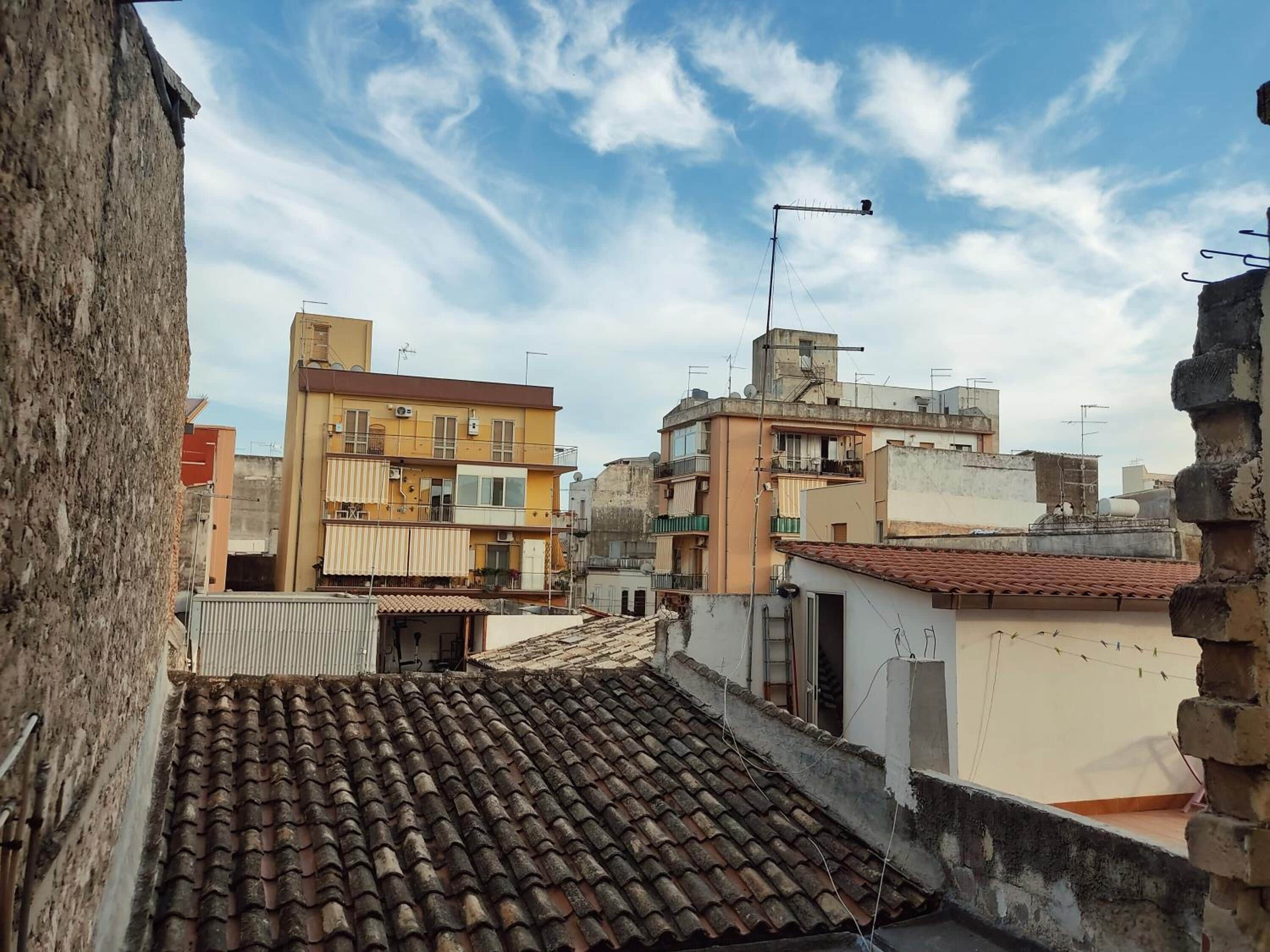 Vue d’un quartier résidentiel avec plusieurs immeubles, dont un bâtiment jaune doté de balcons et un bâtiment blanc avec un toit en tuiles.
