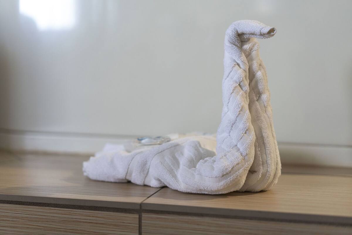 A swan-shaped towel on a wooden floor.