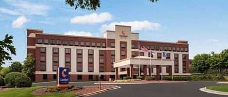 Un hotel Comfort Inn con fachada de ladrillo, múltiples ventanales y aparcamiento.