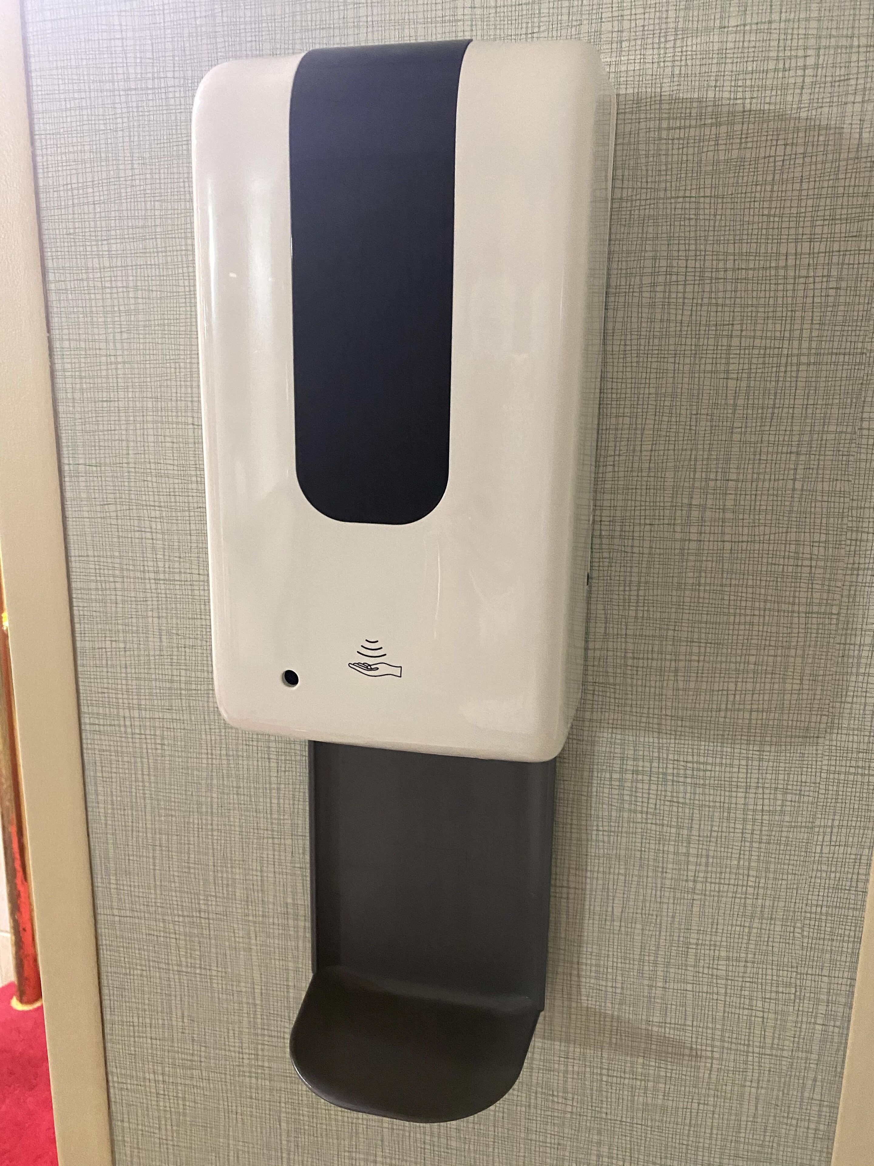 A wall-mounted hand sanitizer dispenser with a black top and a grey base.