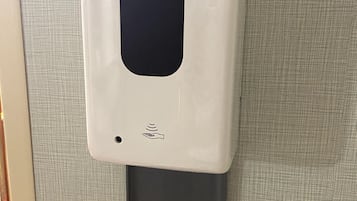 A wall-mounted hand sanitizer dispenser with a black top and a grey base.