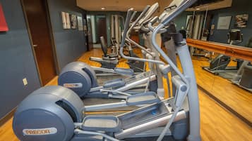 Un gimnasio con varias máquinas de ejercicio, incluyendo cintas de correr y elípticas.