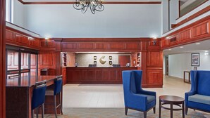 A lobby with wooden paneling, a reception desk, blue chairs, and a patterned carpet. - Comfort Suites Outlet Center (Asheville)