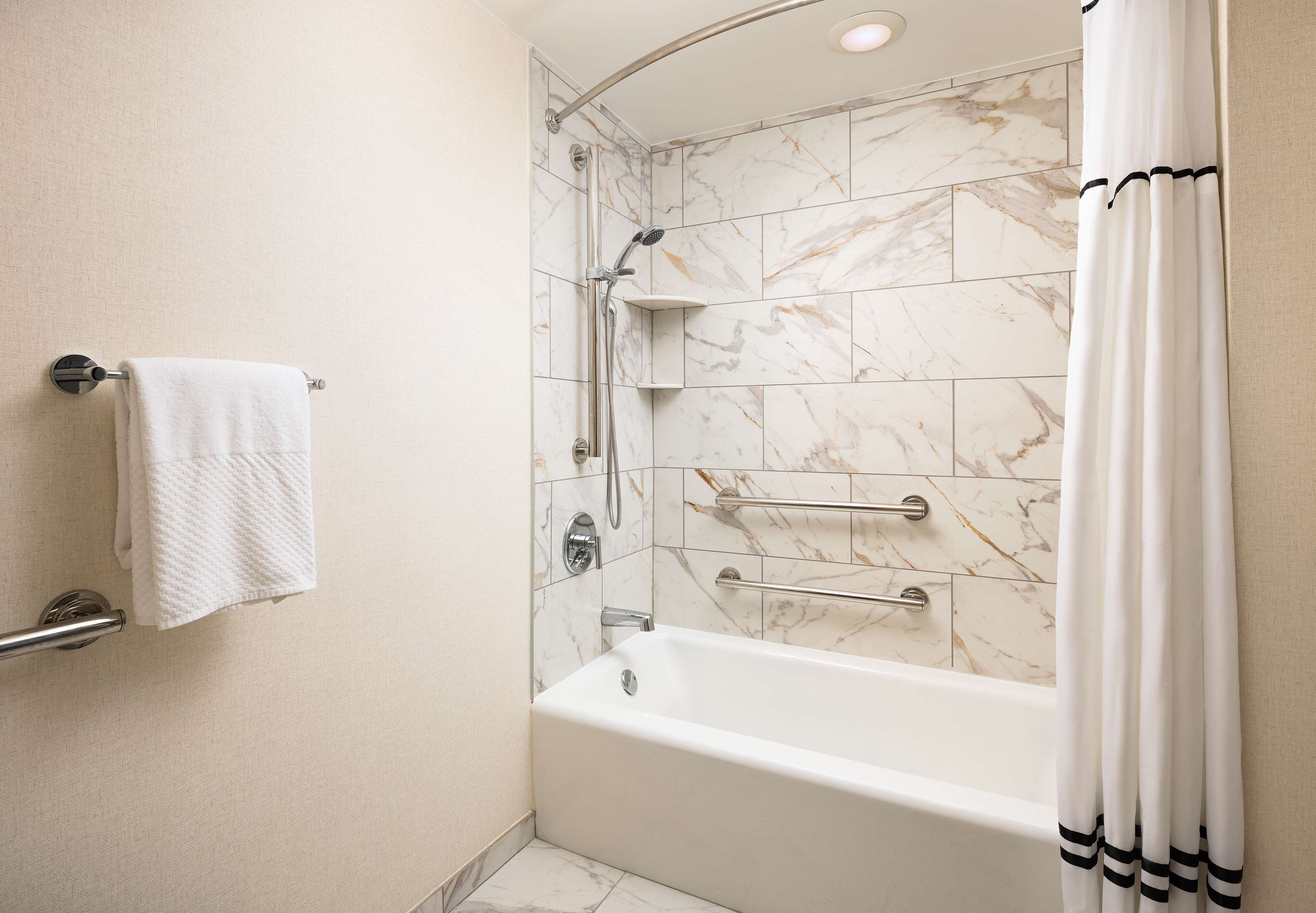Un baño moderno con bañera, ducha y perchero.