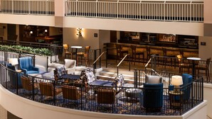 A multi-level hotel lobby with a bar area, seating arrangements, and a staircase. - Embassy Suites by Hilton Atlanta Buckhead (Atlanta)