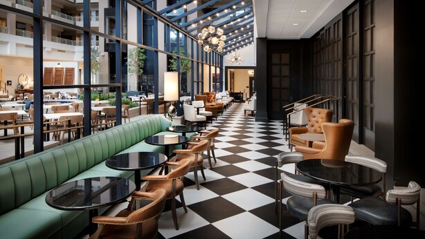 A spacious indoor area with a checkered floor, green seating, and multiple tables and chairs. - Embassy Suites by Hilton Atlanta Buckhead (Atlanta)