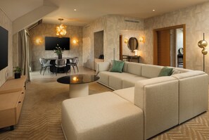 A modern living room with a sectional sofa, a coffee table, and a dining area with chairs and a TV. - Hilton Milan (Milan)