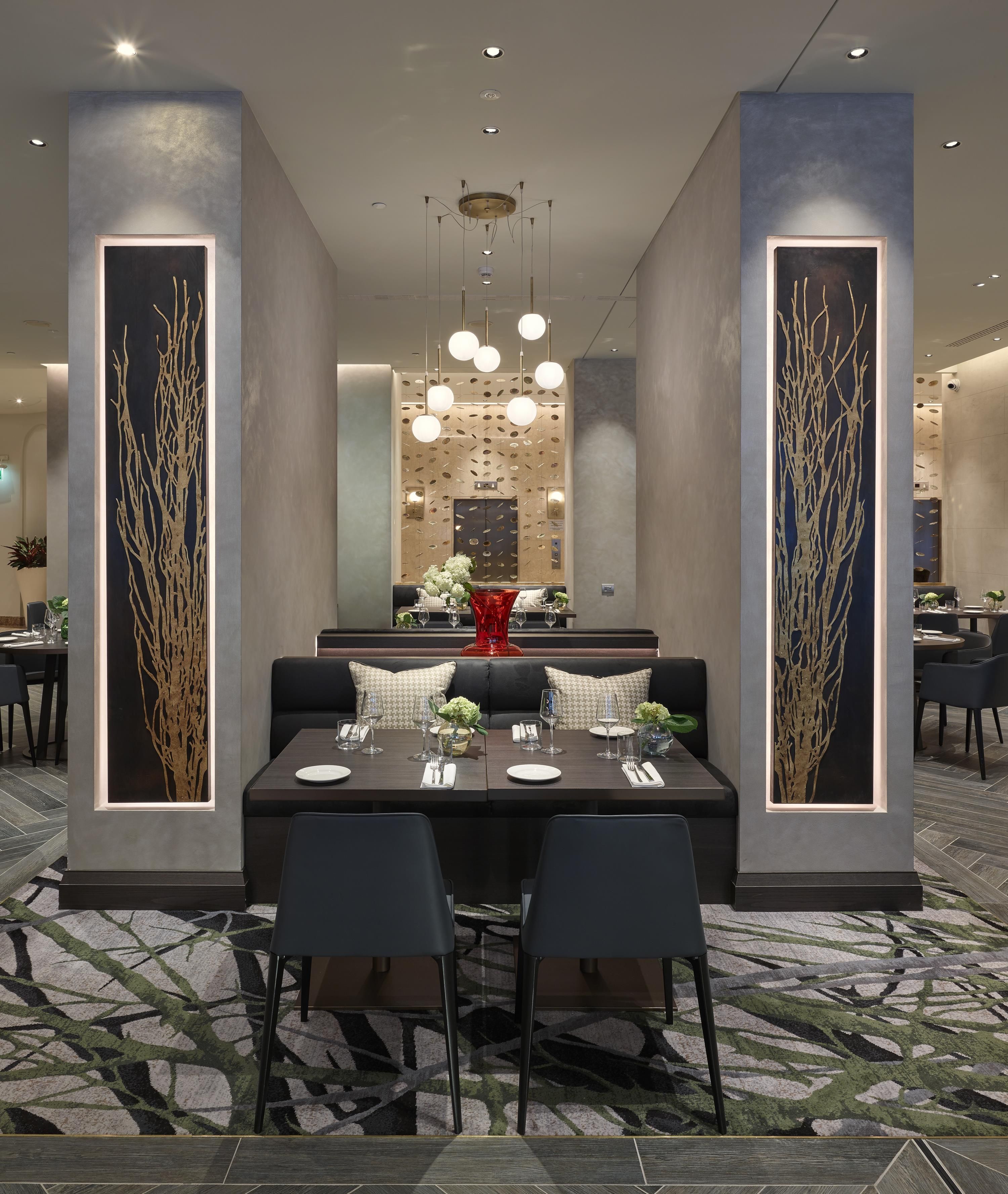 Un comedor moderno con una mesa rectangular, sillas negras y una alfombra estampada.